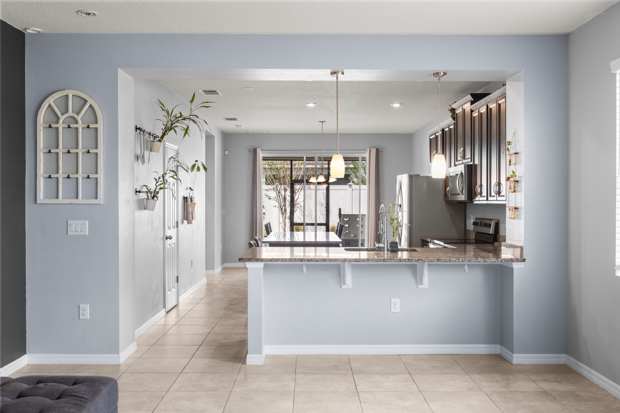 2401 Avian Loop Kissimmee FL - Wide view from living room looking across the granite breakfast bar into the kitchen, dining area, and lanai doors