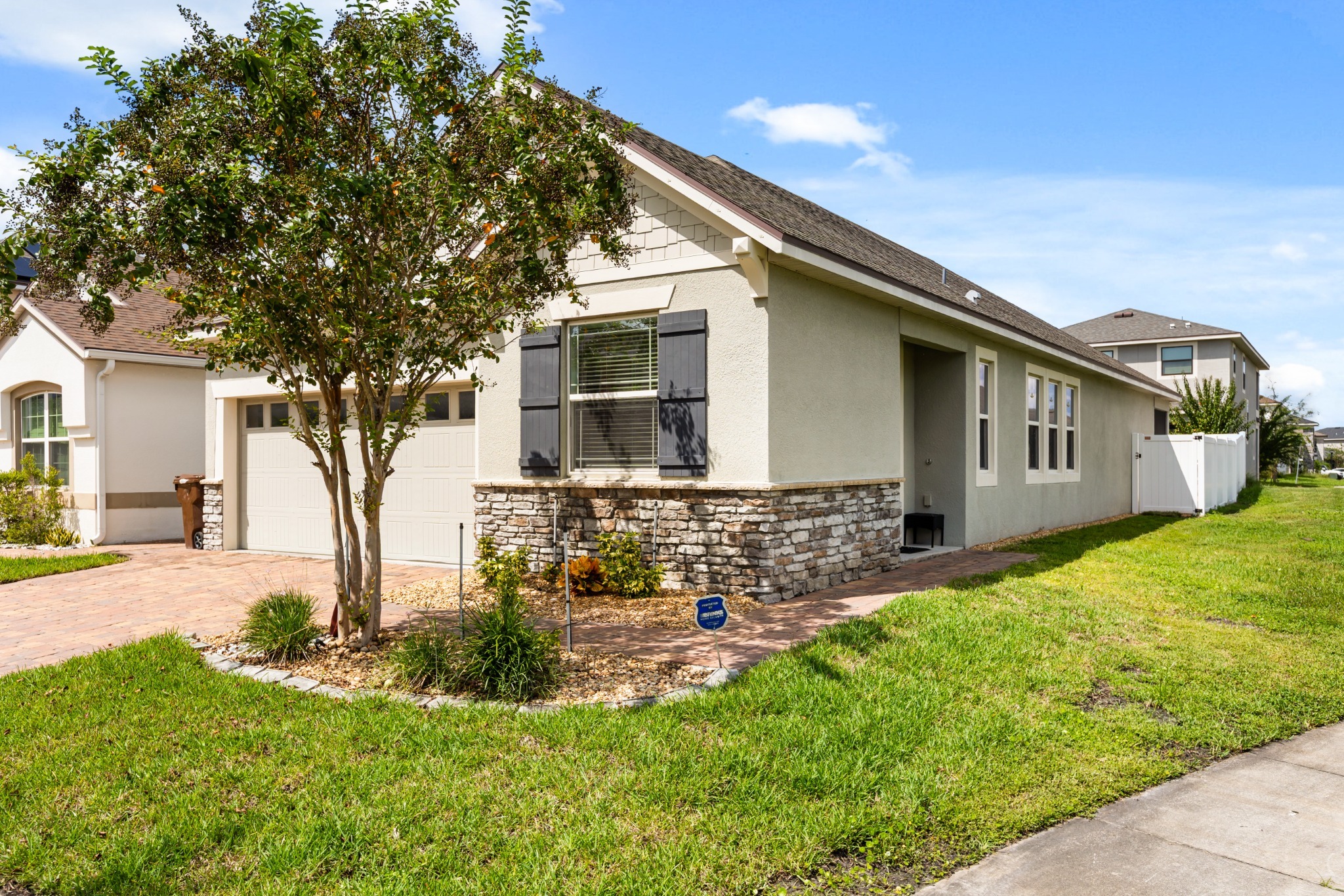 2401 Avian Loop Kissimmee FL - Angled exterior view highlighting architectural details, paved driveway, stone accents, and shade tree