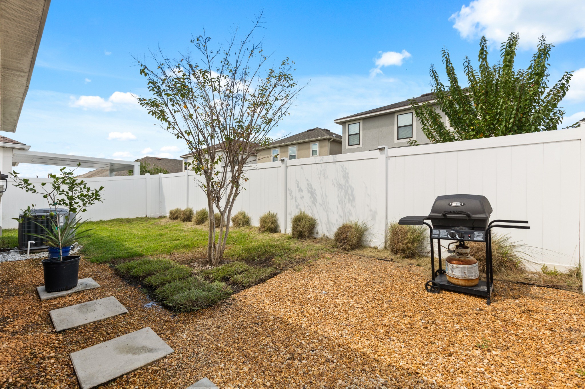 2401 Avian Loop Kissimmee FL - Private fenced backyard with paver stepping stones, landscape bed, and white privacy fence