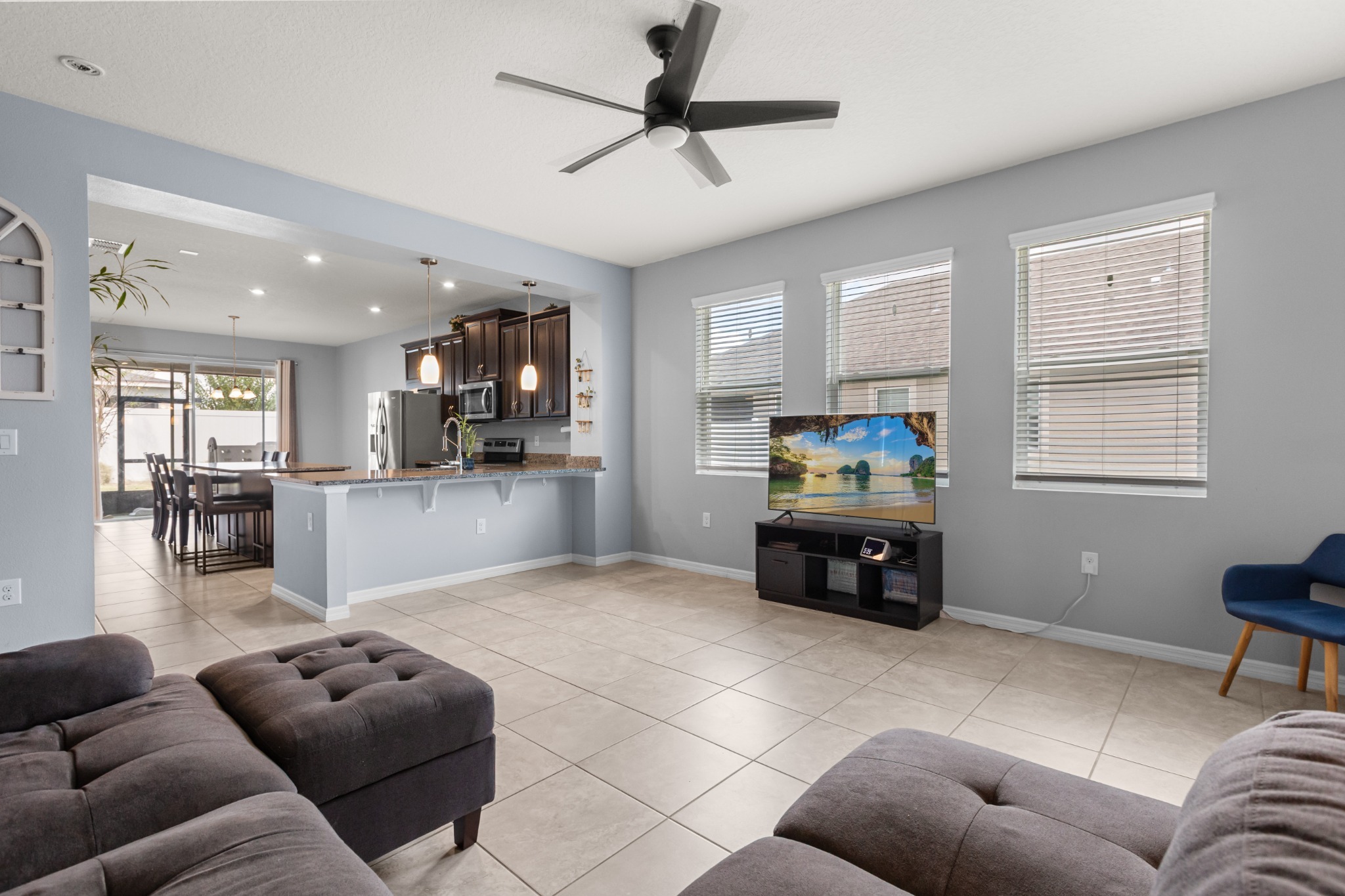 2401 Avian Loop Kissimmee FL - Alternate angle of open living room showing ceramic tile flooring, kitchen bar seating, and bright window line