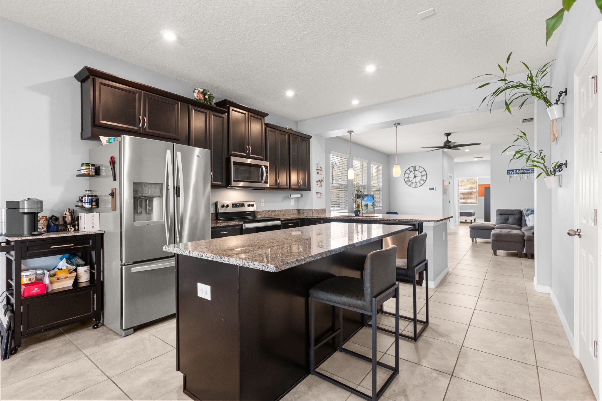 2401 Avian Loop Kissimmee FL - Kitchen interior angle featuring stainless steel refrigerator, center island seating, and view extending into living room