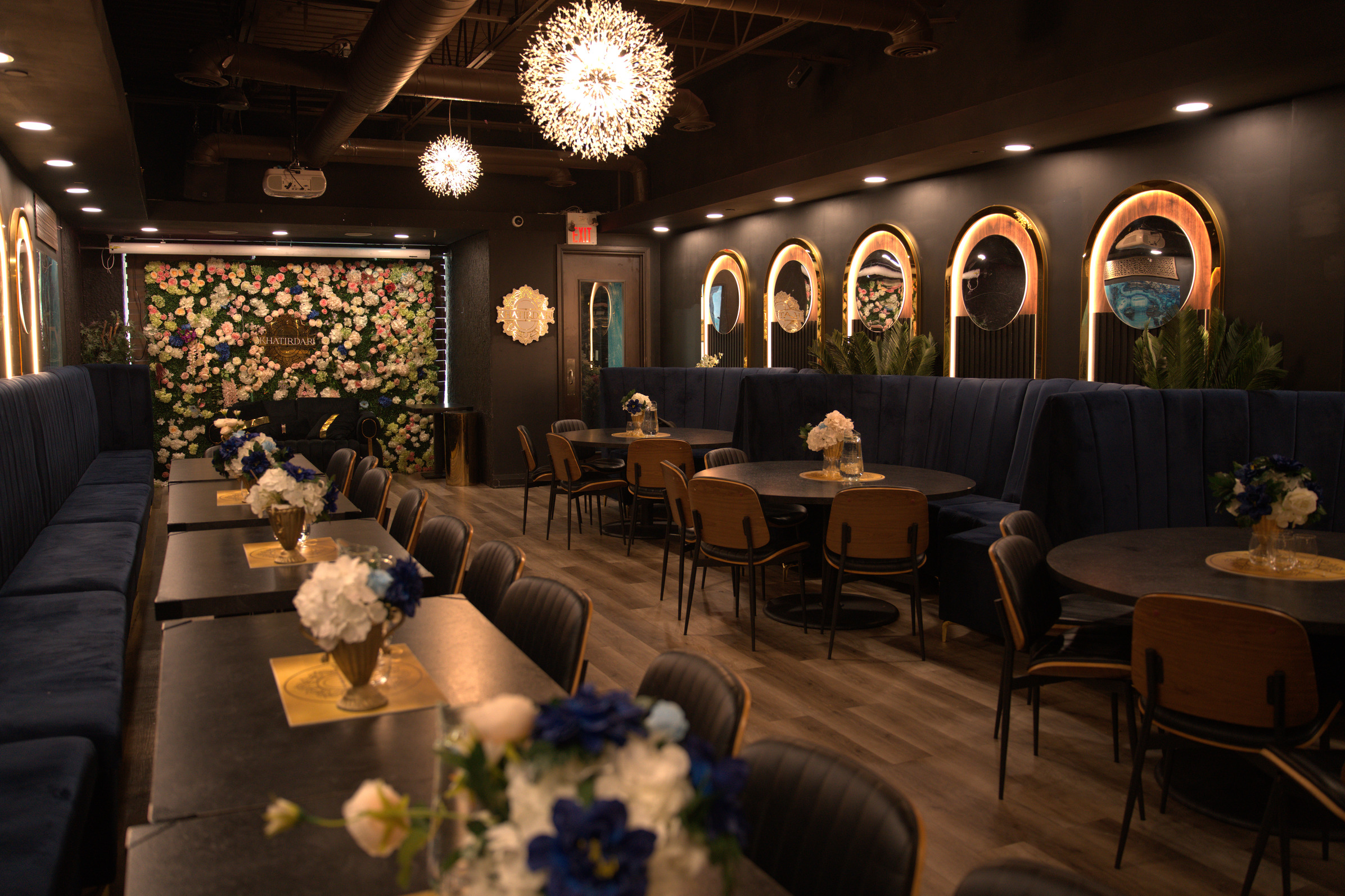 Khatirdari event venue interior Brampton showing floral wall backdrop and round dining tables