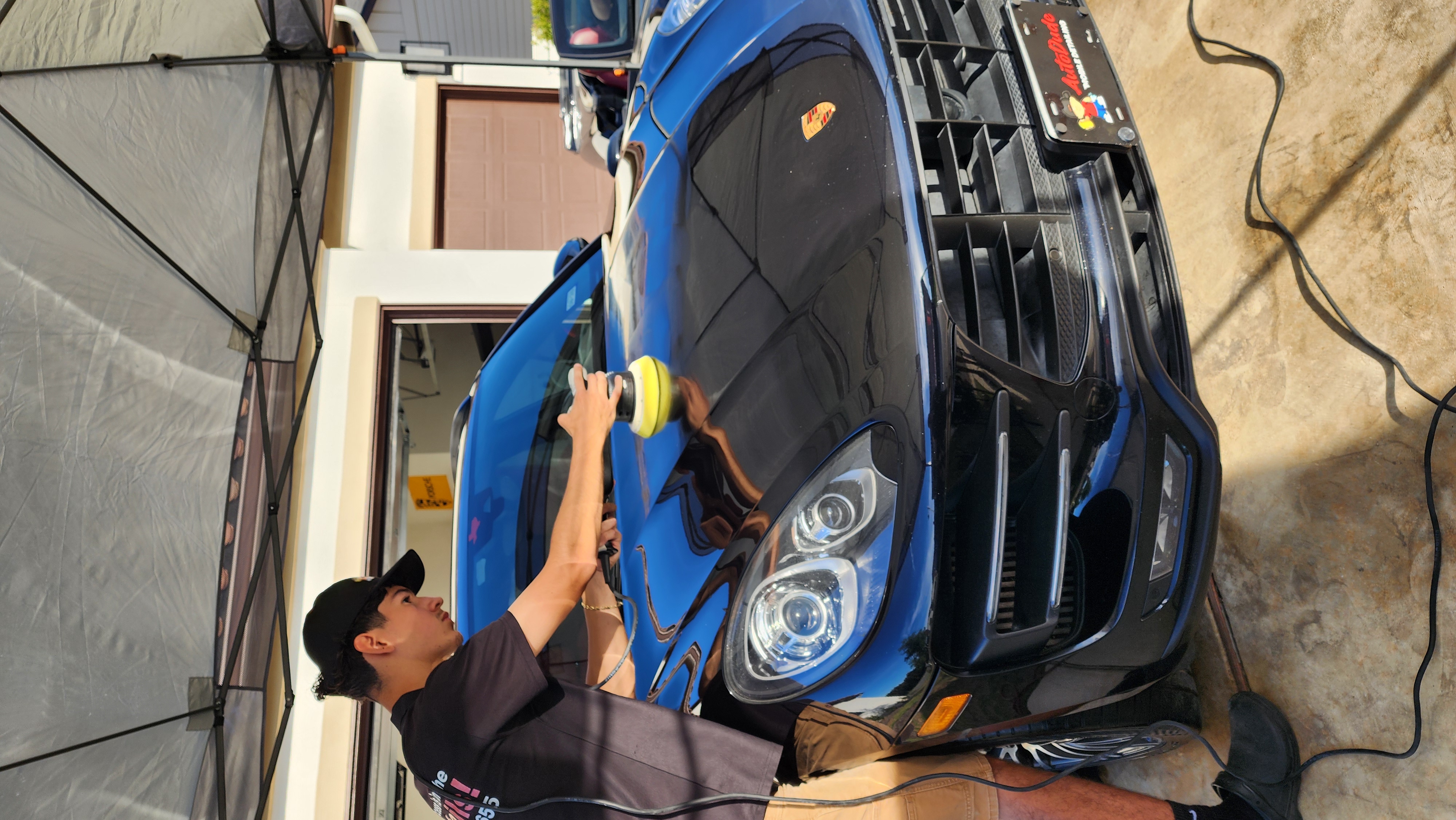 Auto Dude technician machine-polishing a black Porsche during paint correction in New Braunfels