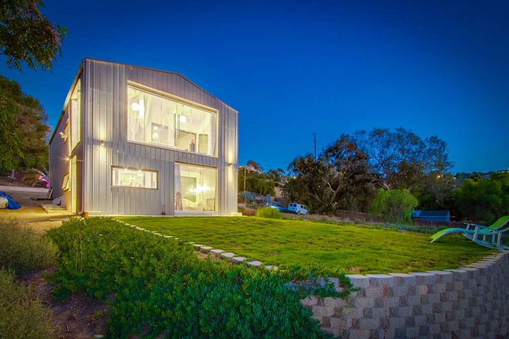 Completed modern two-story steel home illuminated at dusk.