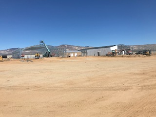 Wide construction site with several steel building frames and completed metal buildings.