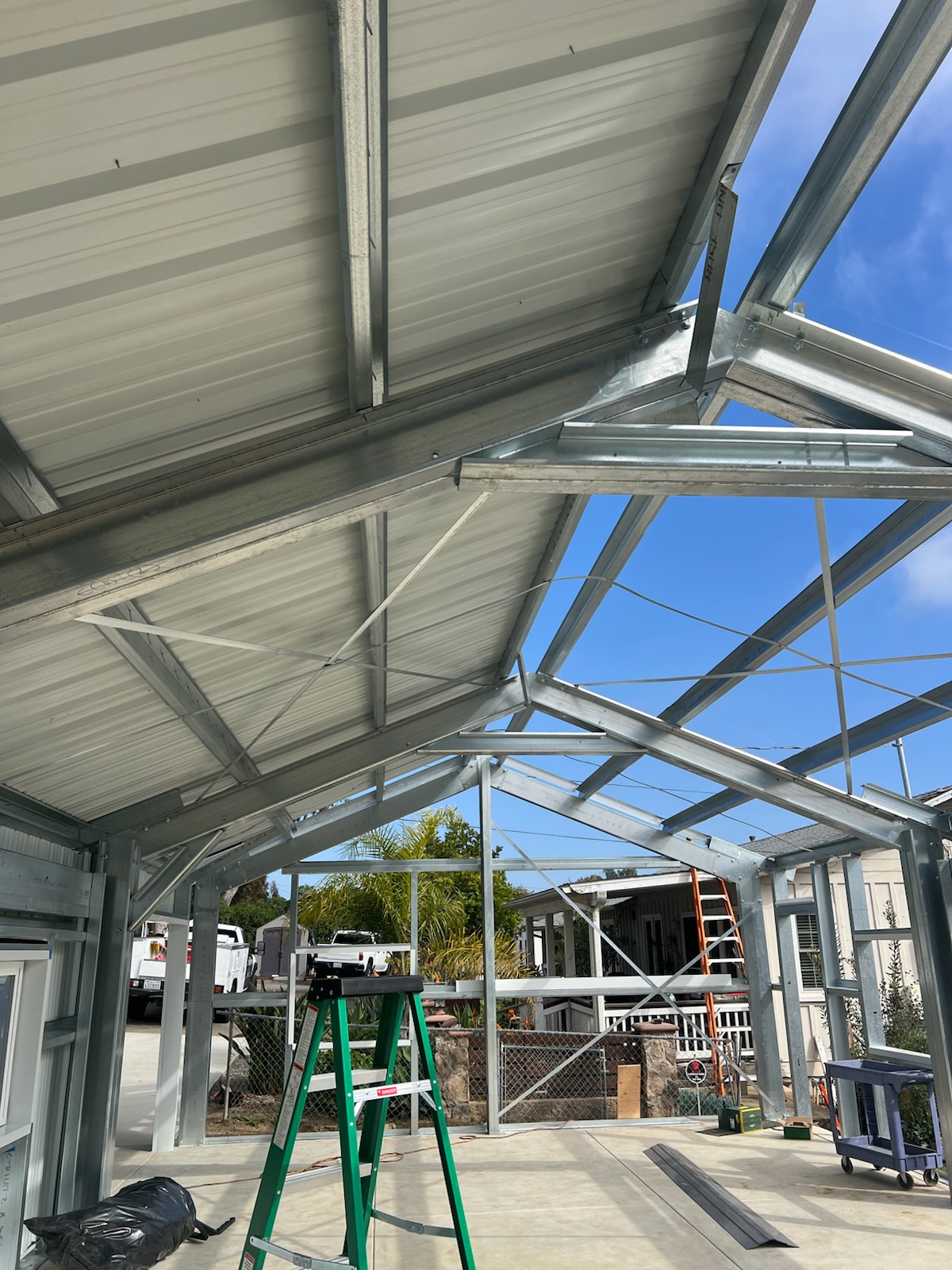 Interior view of galvanized steel roof framing and partially installed metal roof panels.