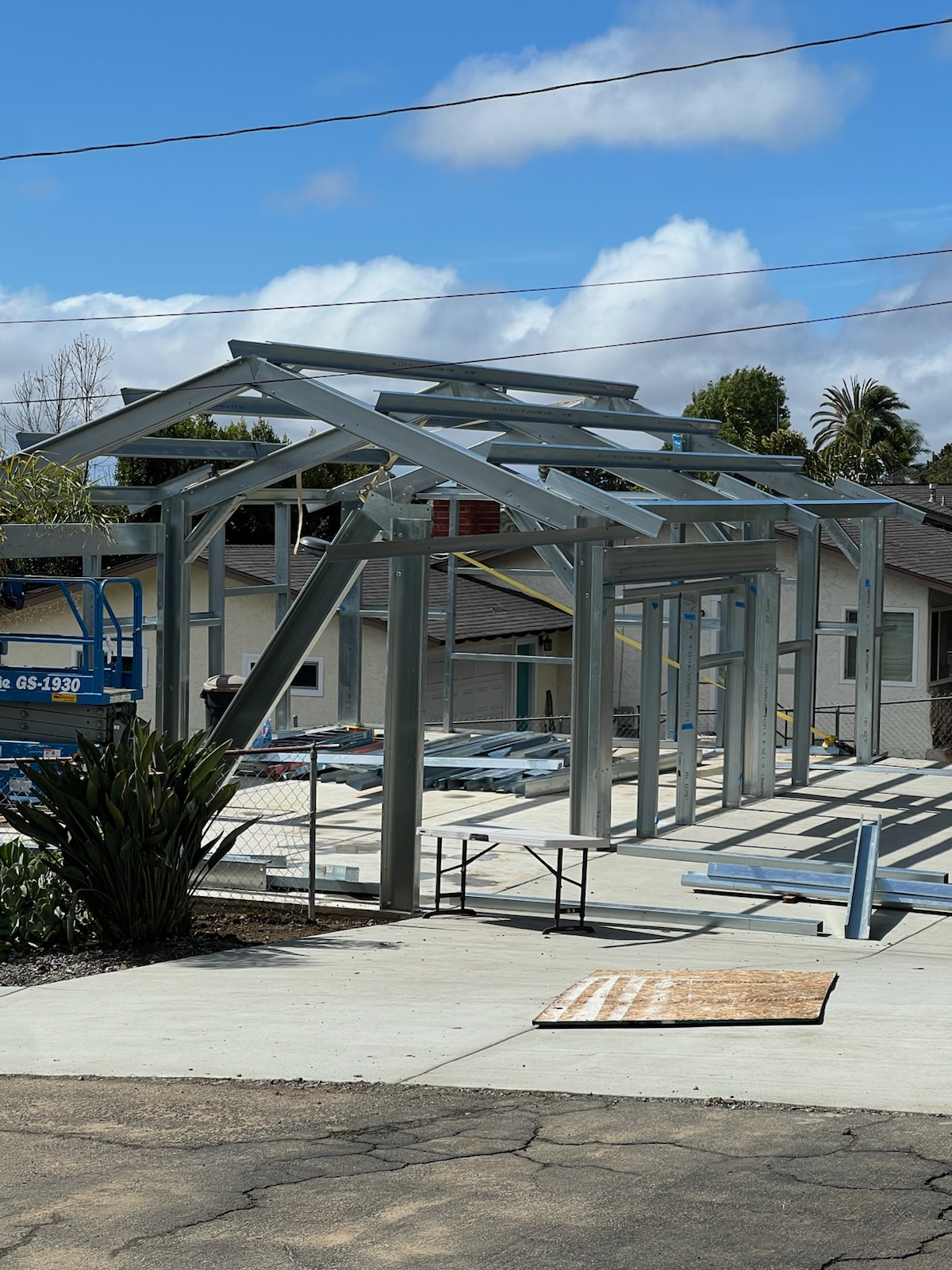 Galvanized steel wall and roof framing during assembly on a concrete slab.