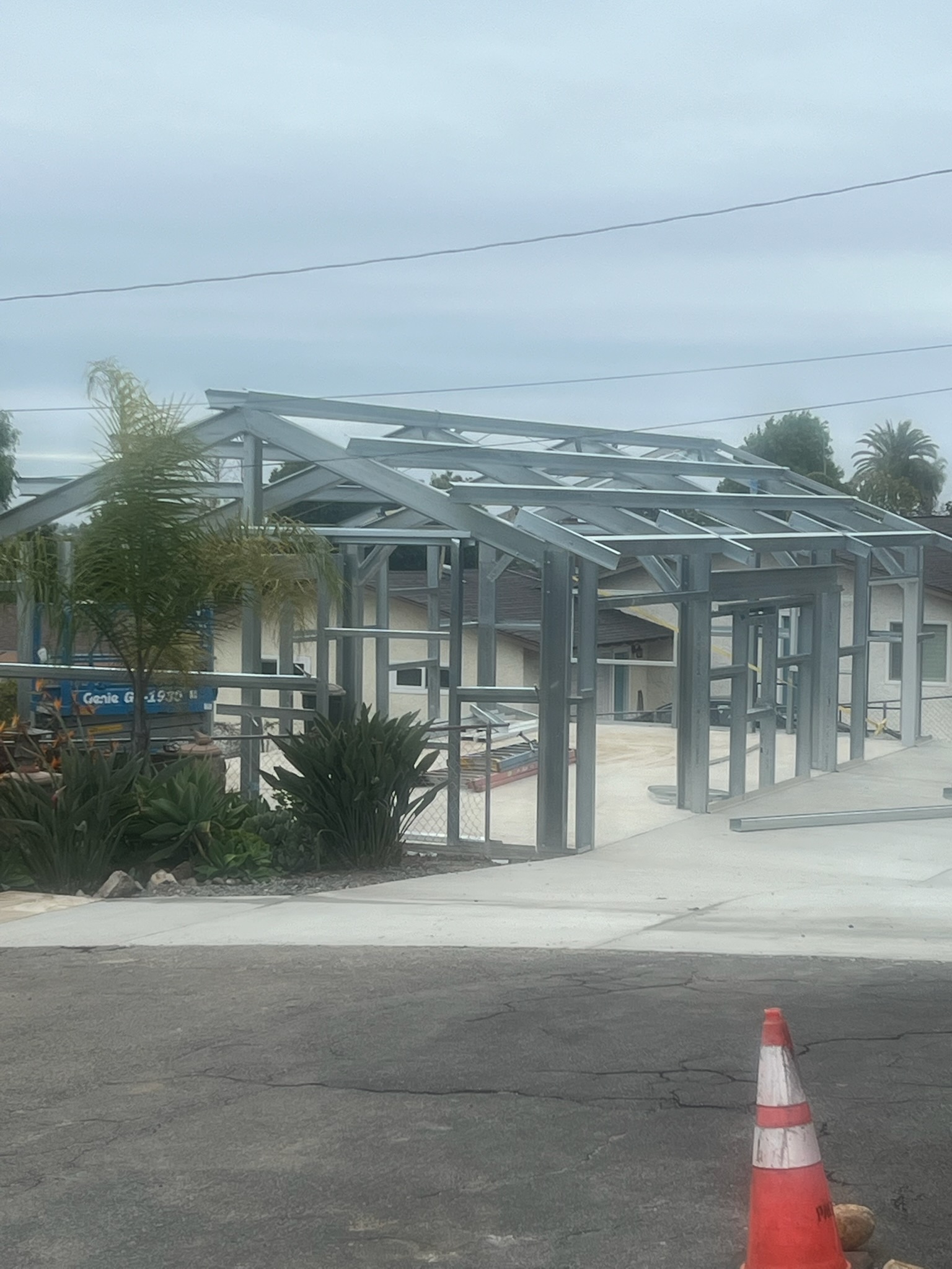 Early roof framing stage of a steel building project viewed from the street.
