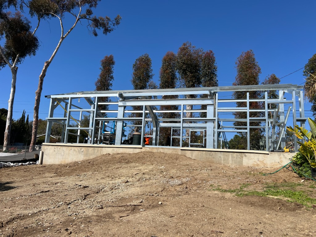 Front view of a galvanized steel building frame installed on a raised concrete foundation.
