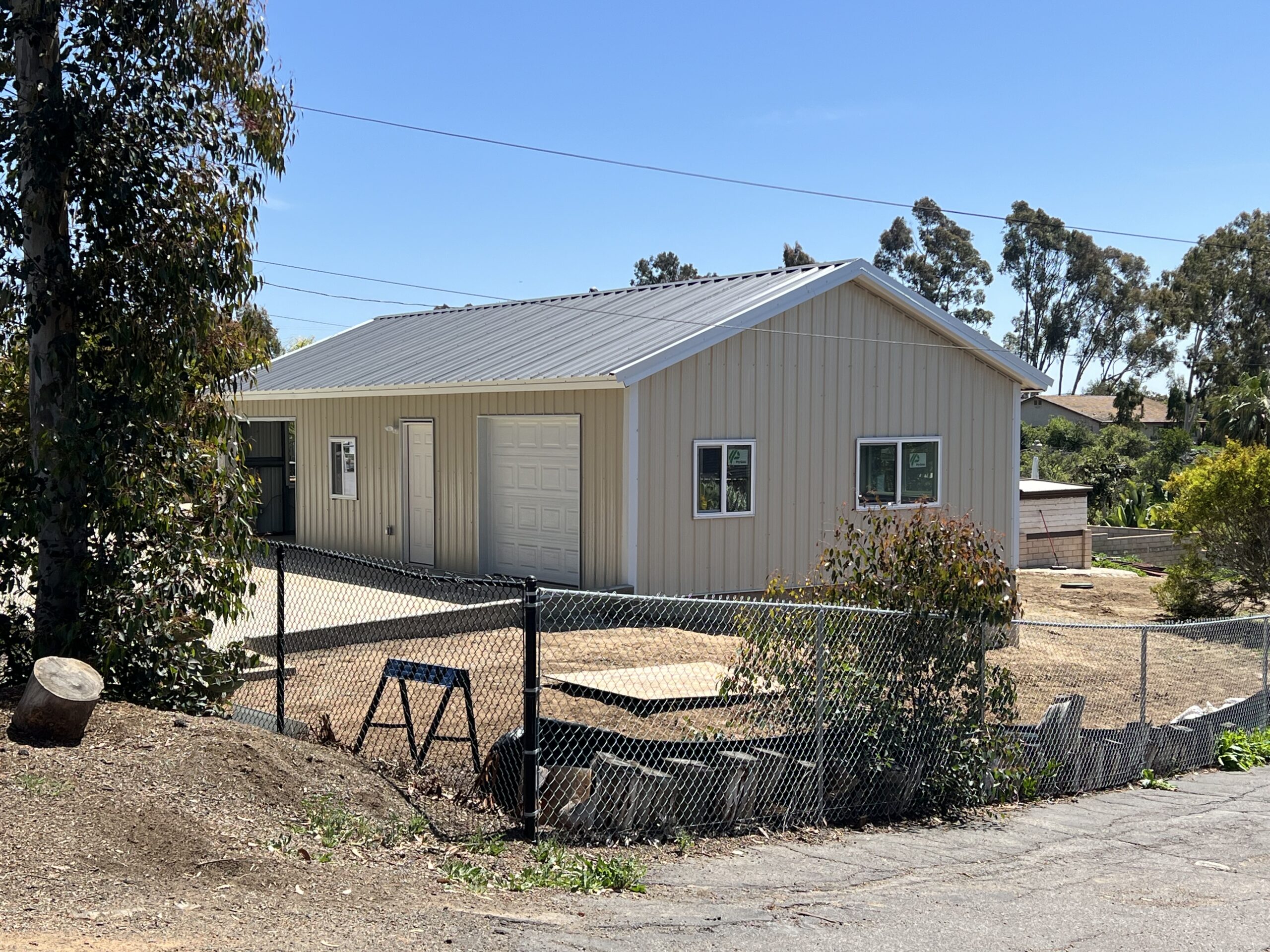 Completed steel workshop with windows, entry door, and a roll-up garage door.