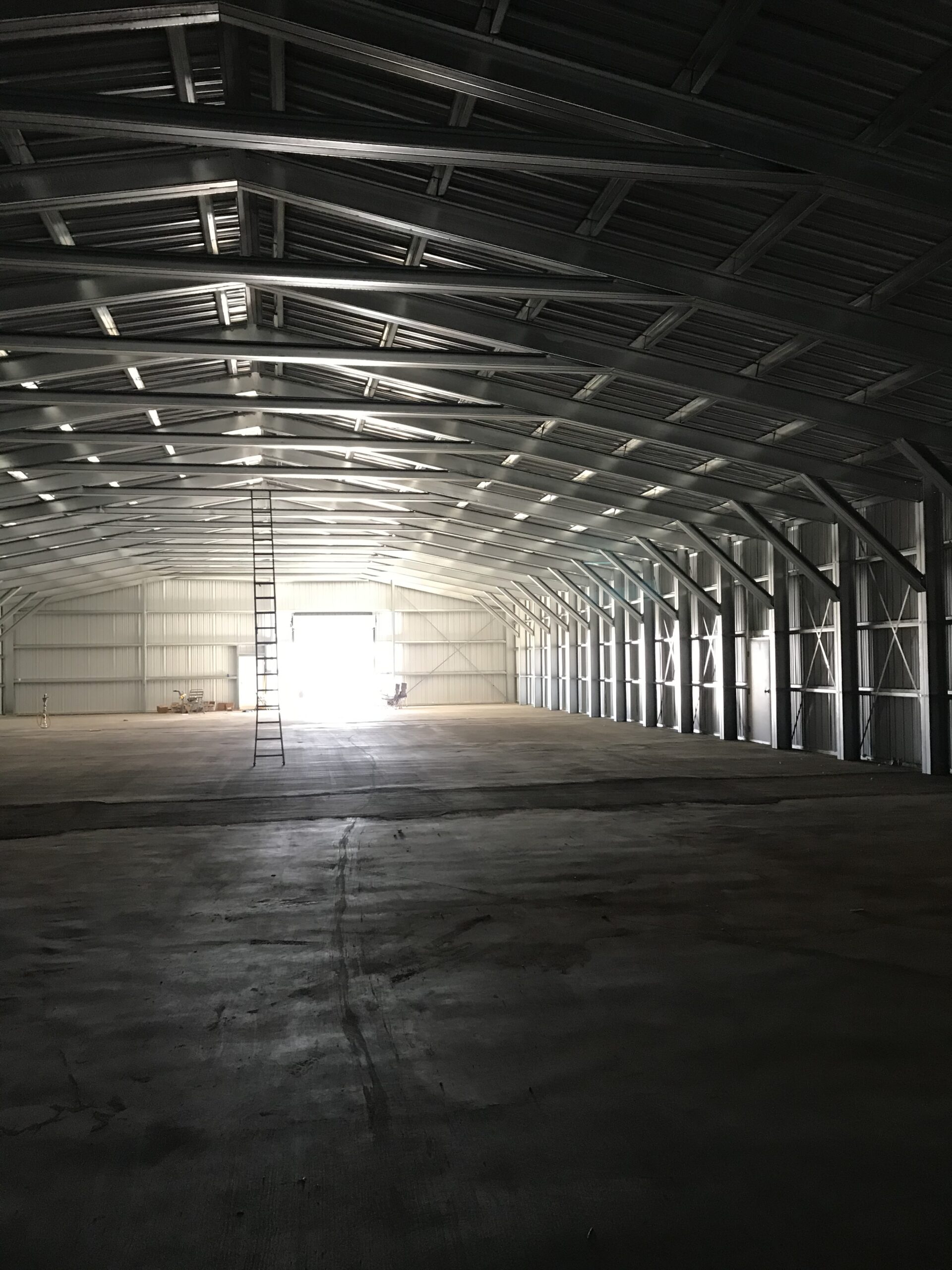 Open finished interior of a long-span steel building with wall and roof panels installed.