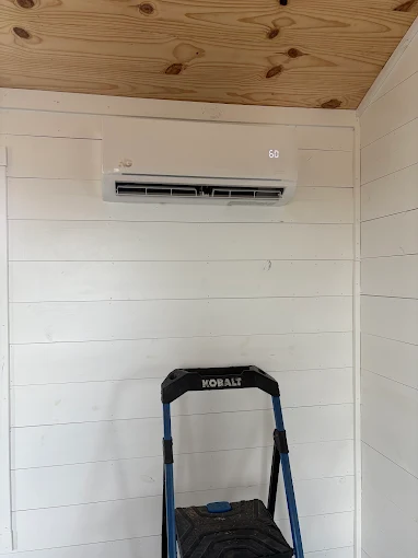 Sleek white wall-mounted mini split air handler in living room in Katy