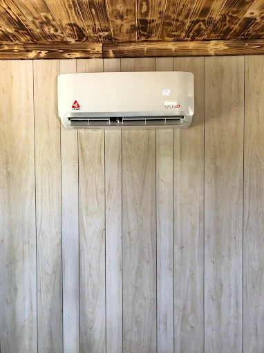 Wall-mounted indoor ductless mini split air handler unit in wood-paneled Pearland room