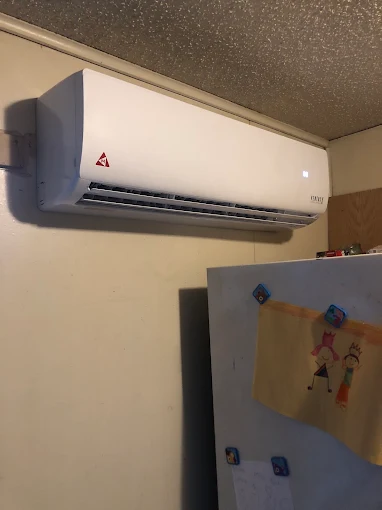 Clean indoor mini split air handler installation above refrigerator in Plano home