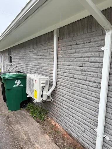 Wall-mounted outdoor mini split unit with clean line cover on gray brick exterior in Cedar Park