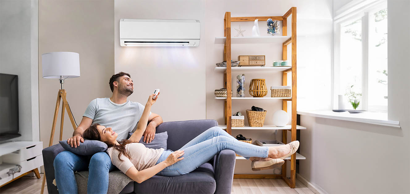 Couple using remote control for wall mounted ductless mini split air handler in Texas living room