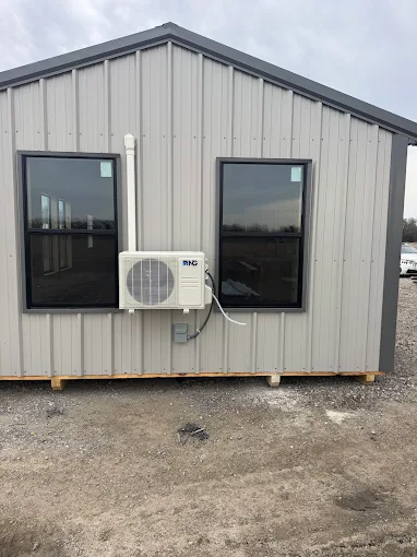 Outdoor ductless mini split heat pump condenser mounted on metal exterior wall in The Woodlands area