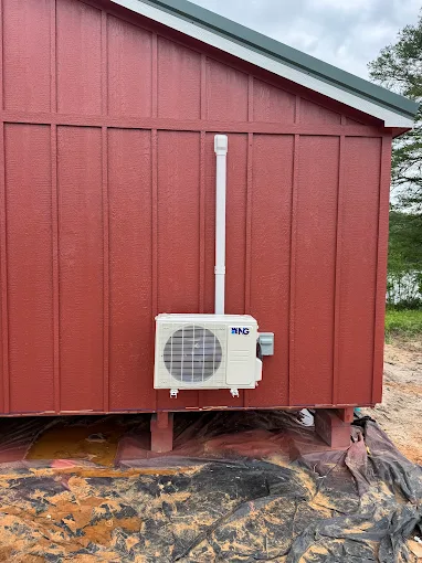 Wall-mounted outdoor mini split unit on red exterior wall in Spring area