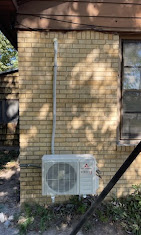 Wall-mounted ductless mini split outdoor condenser on brick wall in The Woodlands