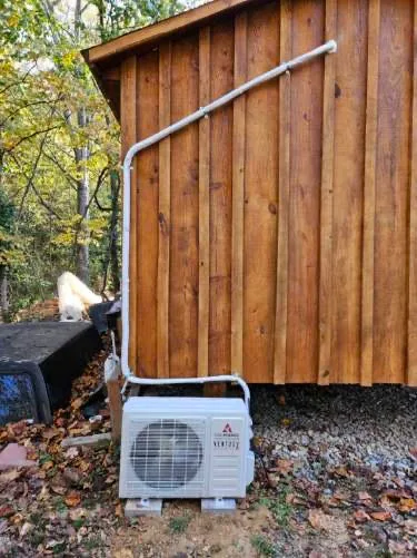 Outdoor mini split condenser unit installed on wooden building exterior in Spring, TX