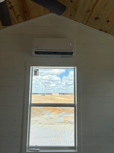 Indoor wall-mounted ductless mini split air handler over window in The Woodlands home