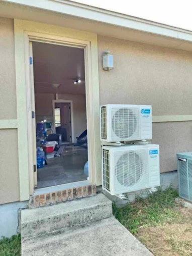 Stacked dual outdoor mini split condensers by exterior doorway in Cedar Park, TX