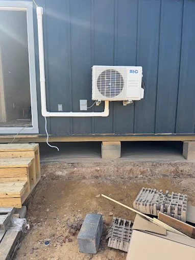 Outdoor ductless mini split heat pump unit wall mounted on exterior wall in Plano