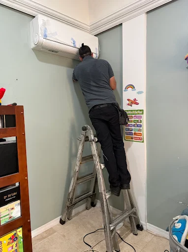 HVAC technician installing indoor ductless mini split wall unit in Round Rock, TX