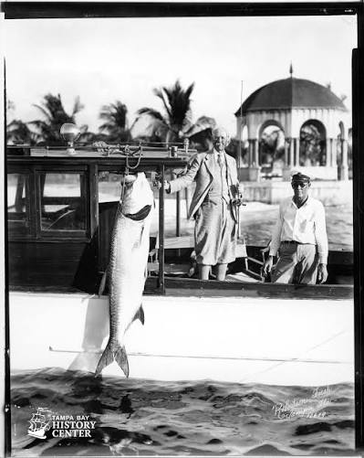 Historic fishing scene showing people aboard a boat with a large catch.