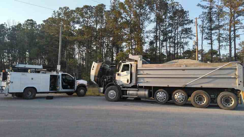 Mobile service truck assisting a large dump truck on a jobsite
