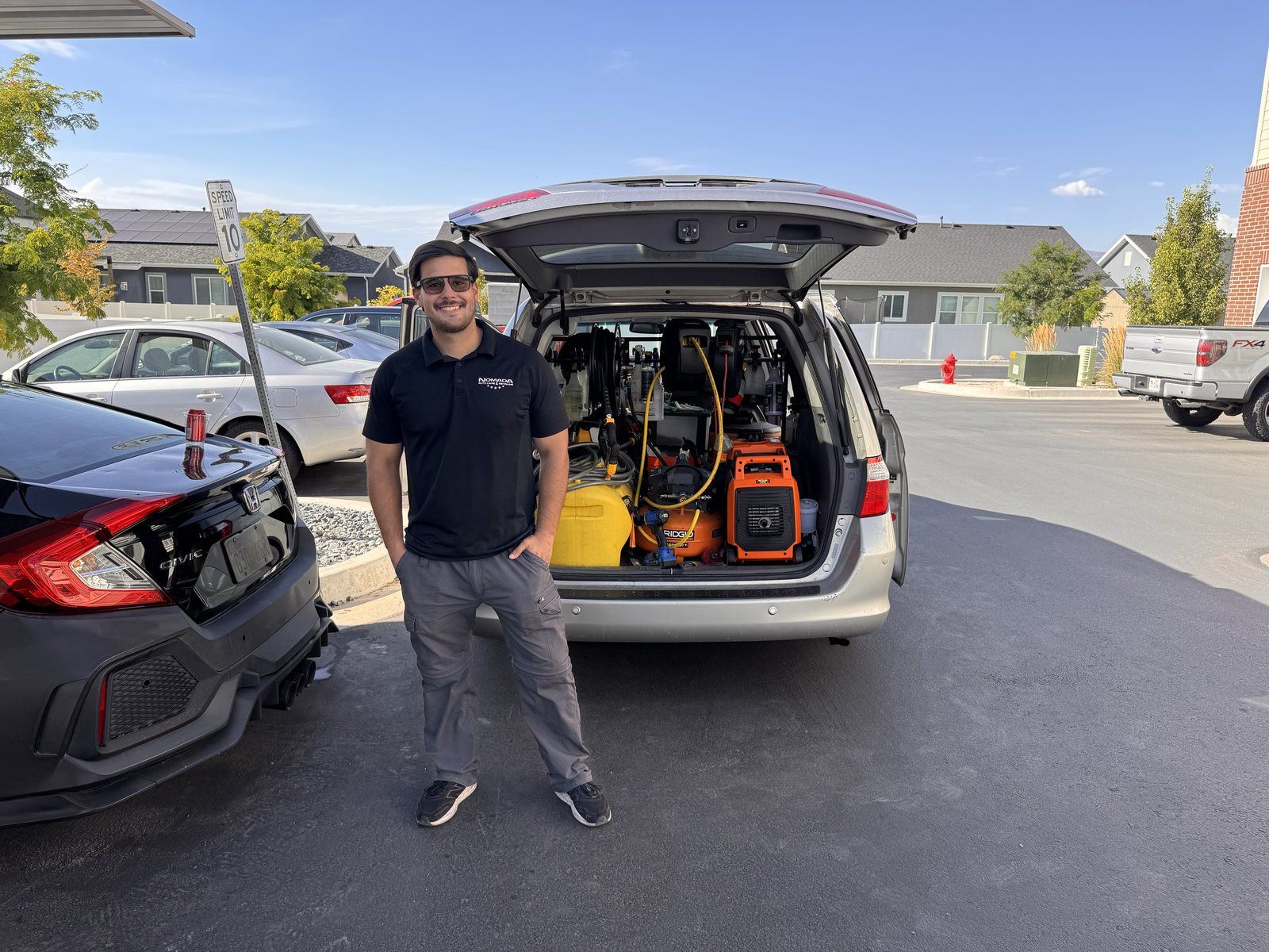 Nomada founder Aaron standing with fully equipped mobile detailing van, showing generator and equipment for on-site service.