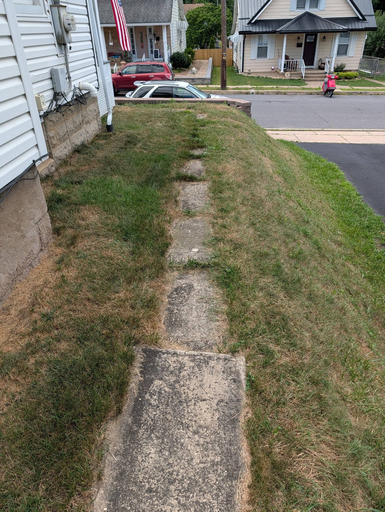 Old cracked concrete sidewalk with weeds growing through