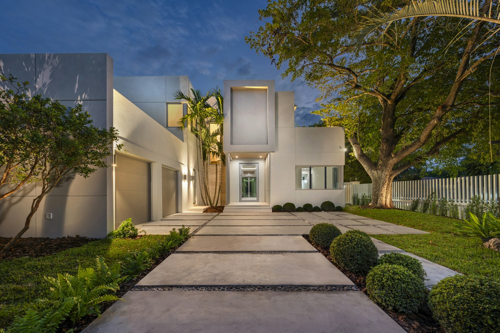 Elegant home exterior with warm landscape uplighting at dusk