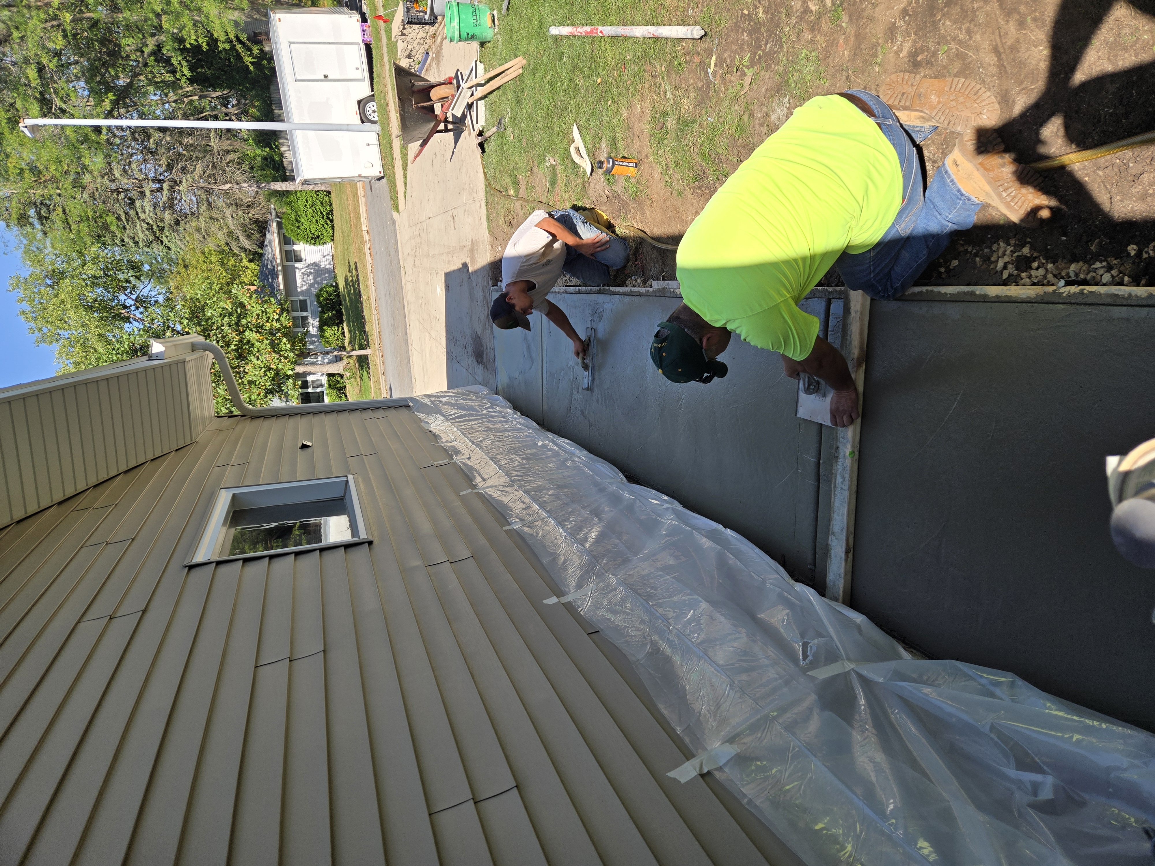 Hand-finishing concrete sidewalk installation along home foundation in Sun Prairie, WI