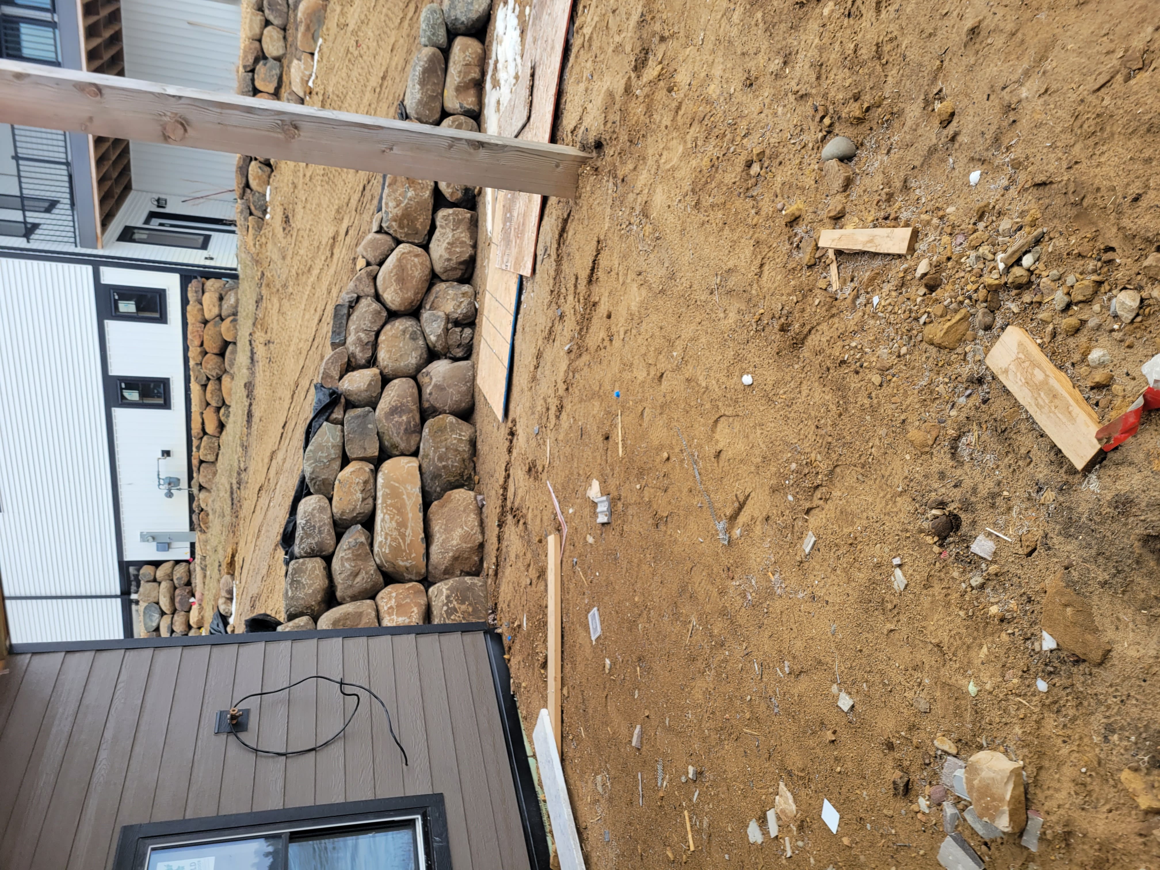 River rock retaining wall construction along house foundation in Dane County, WI