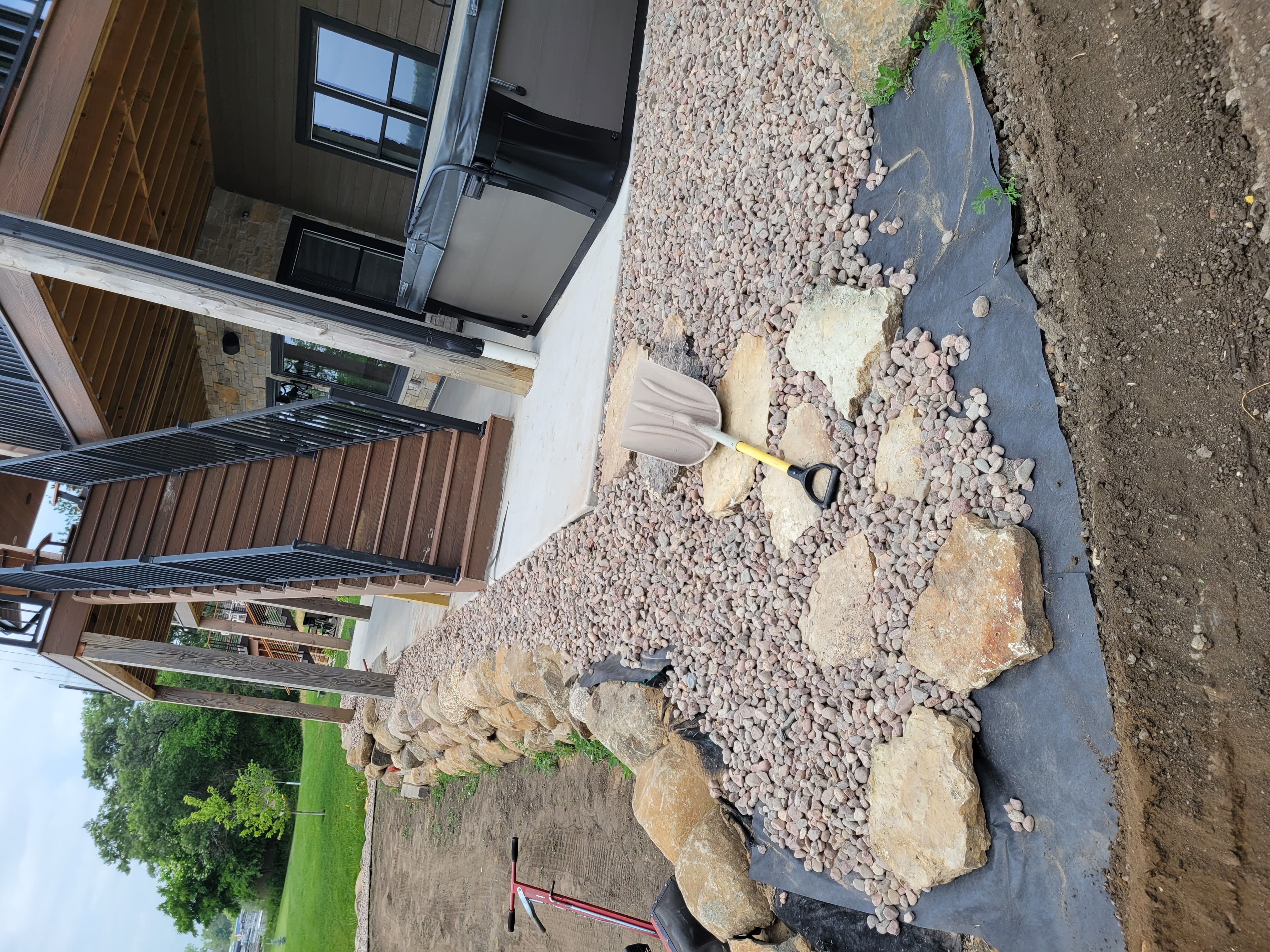 Finished river rock landscape bed with boulder border near home patio in Dane County, WI