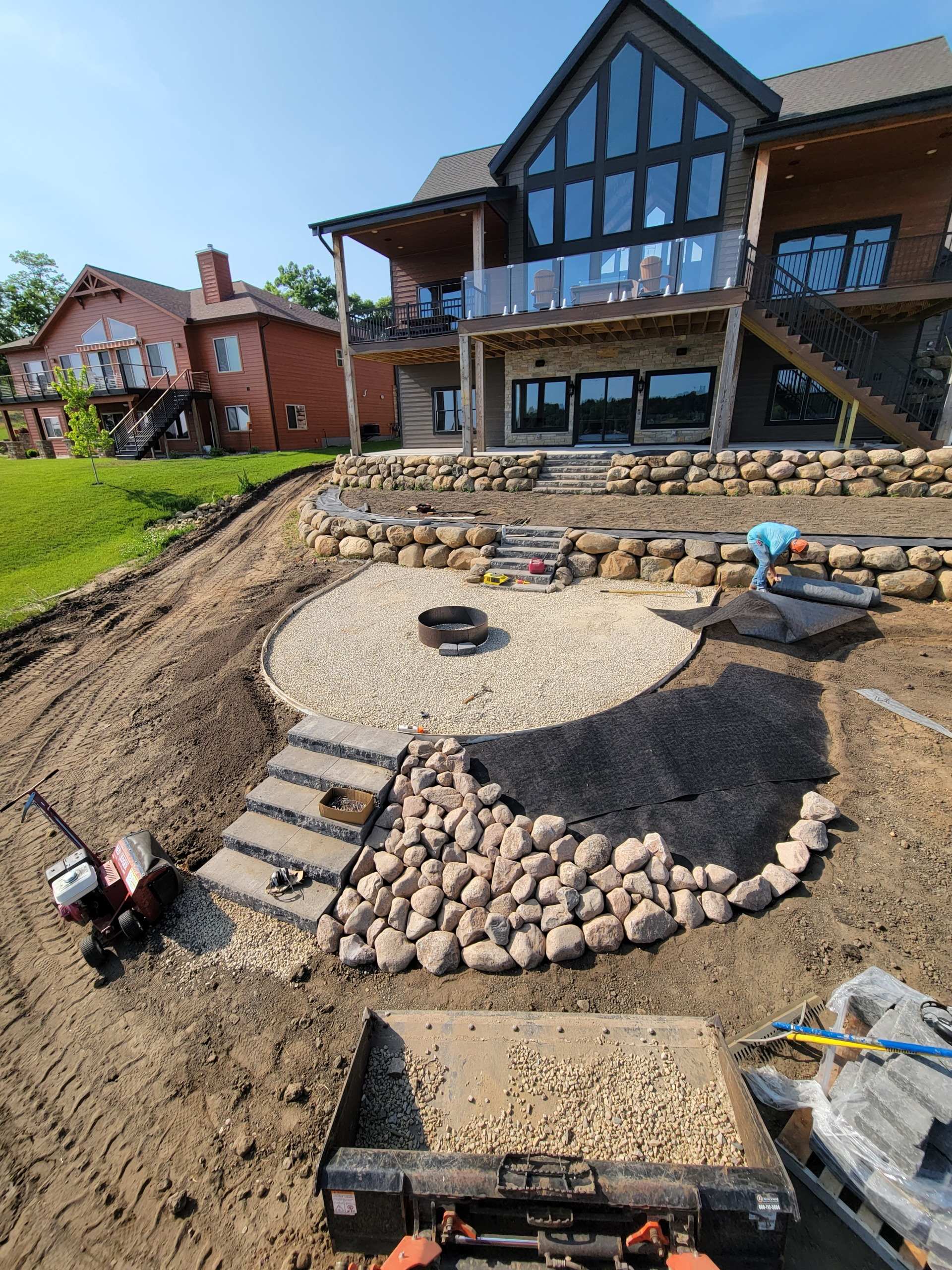 Boulder retaining wall with paver steps and fire pit patio installation in Dane County, WI