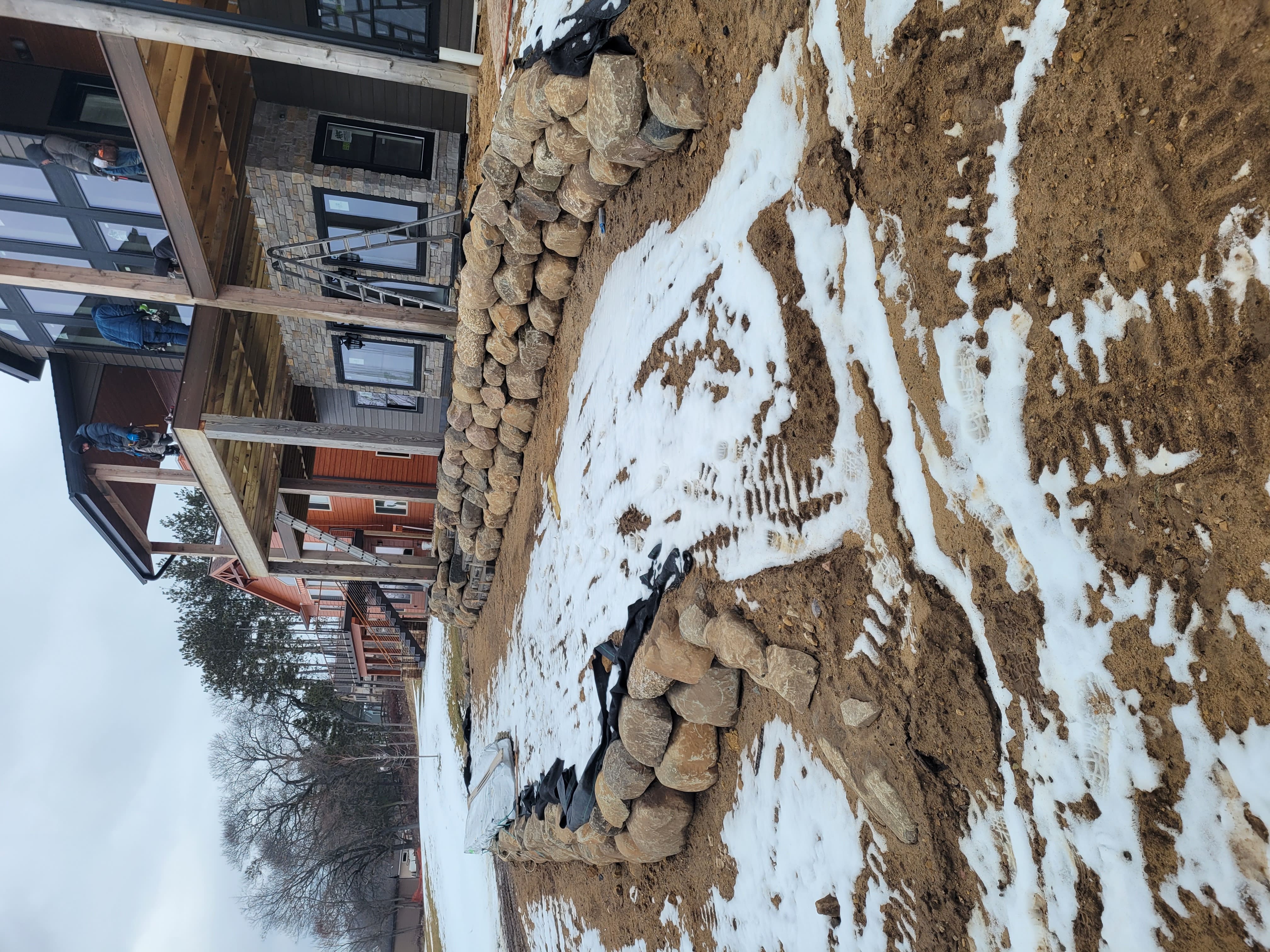 Boulder retaining wall installation with landscape fabric behind lakeside home in Dane County, WI