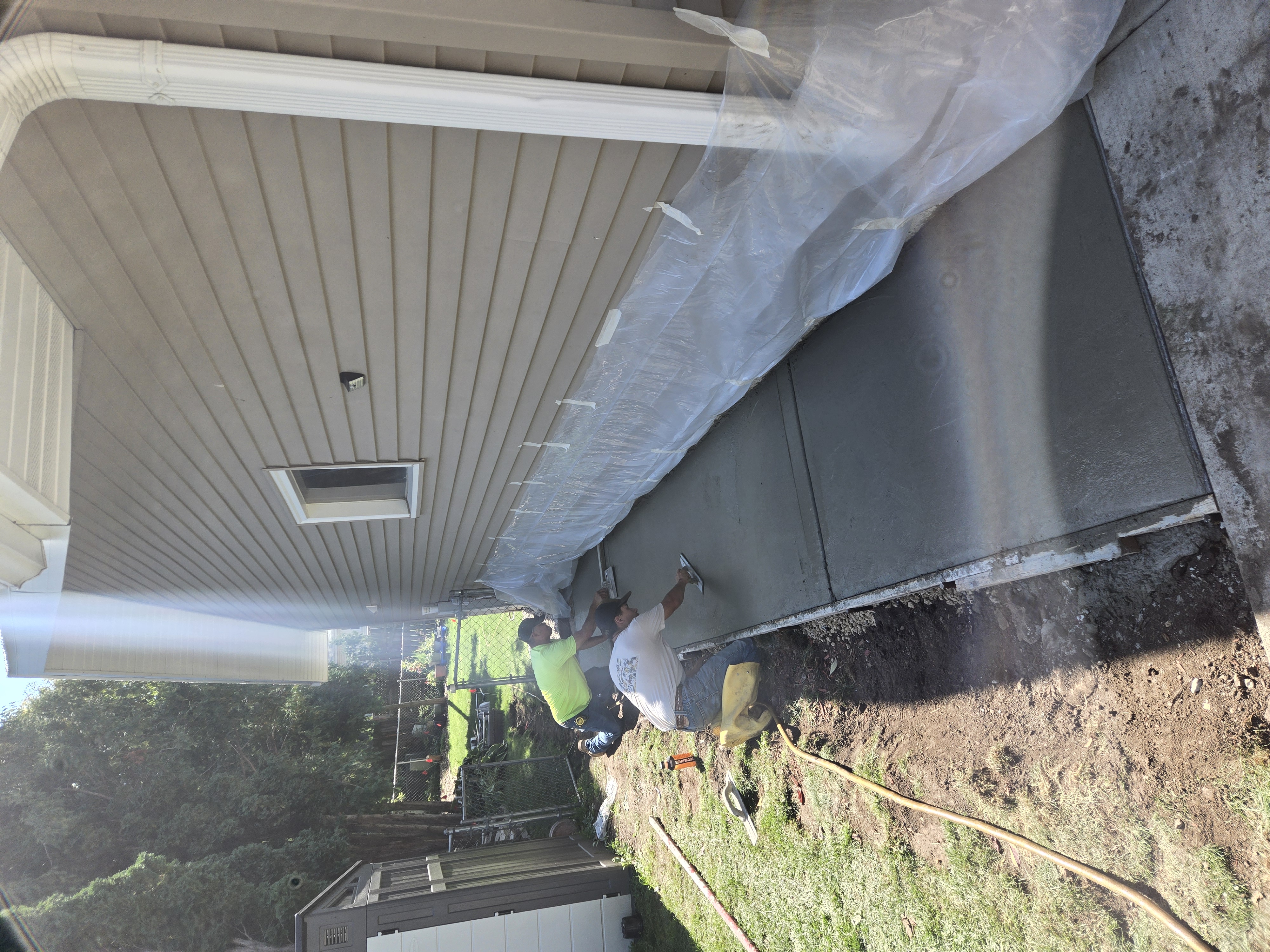 Crew precision troweling concrete patio walkway alongside residential home in Sun Prairie, WI