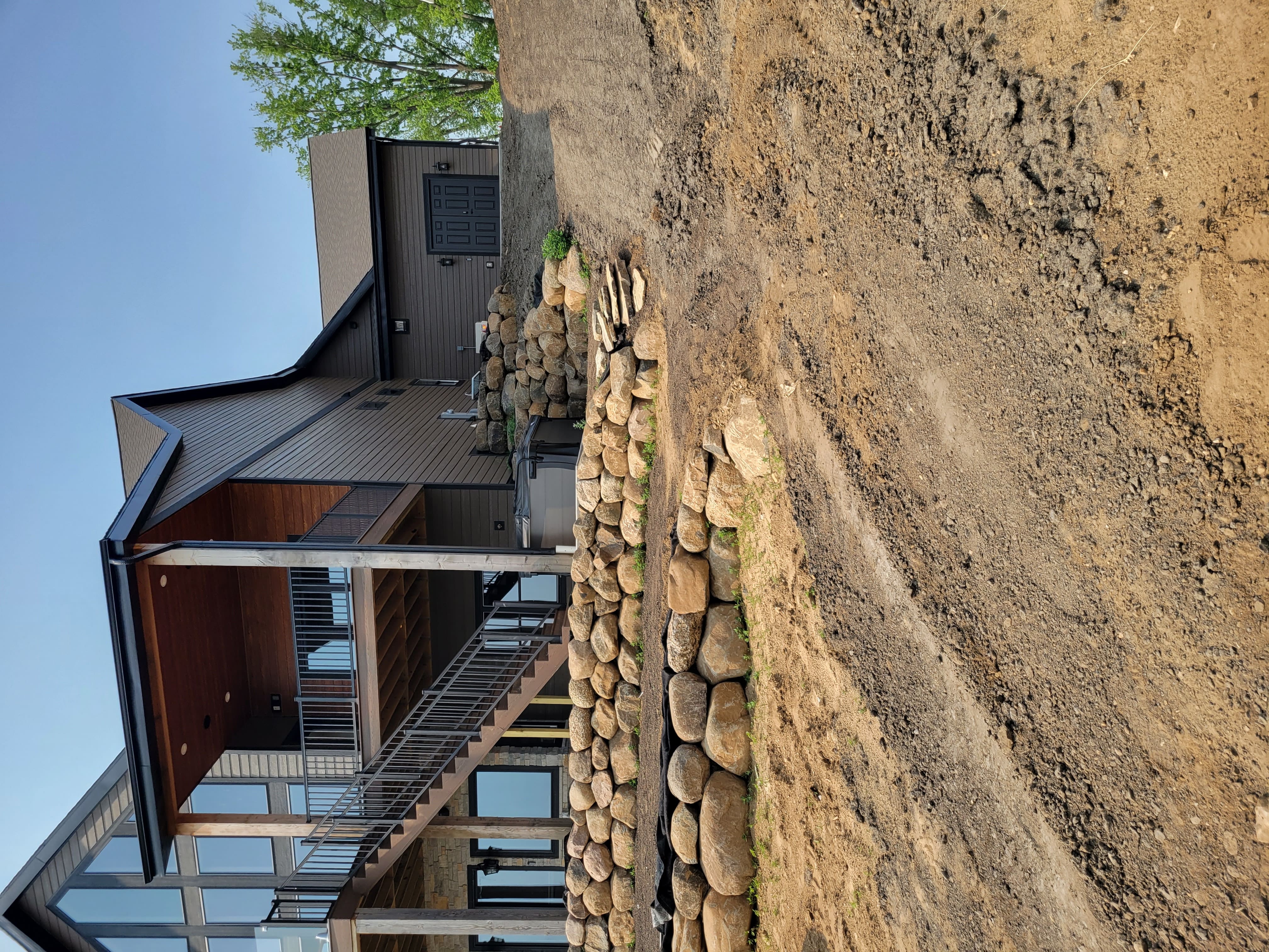 Completed boulder retaining wall with deck and hot tub area at a lakeside home in Dane County, WI