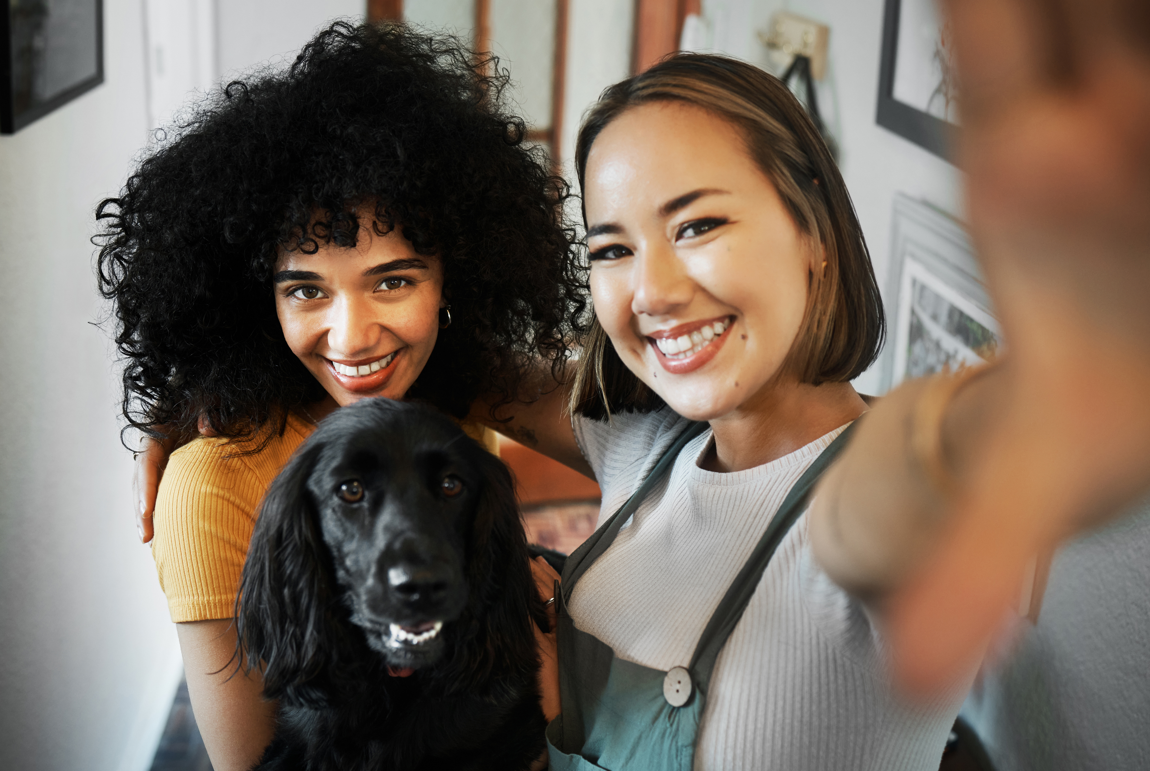Two women smiling with a black dog