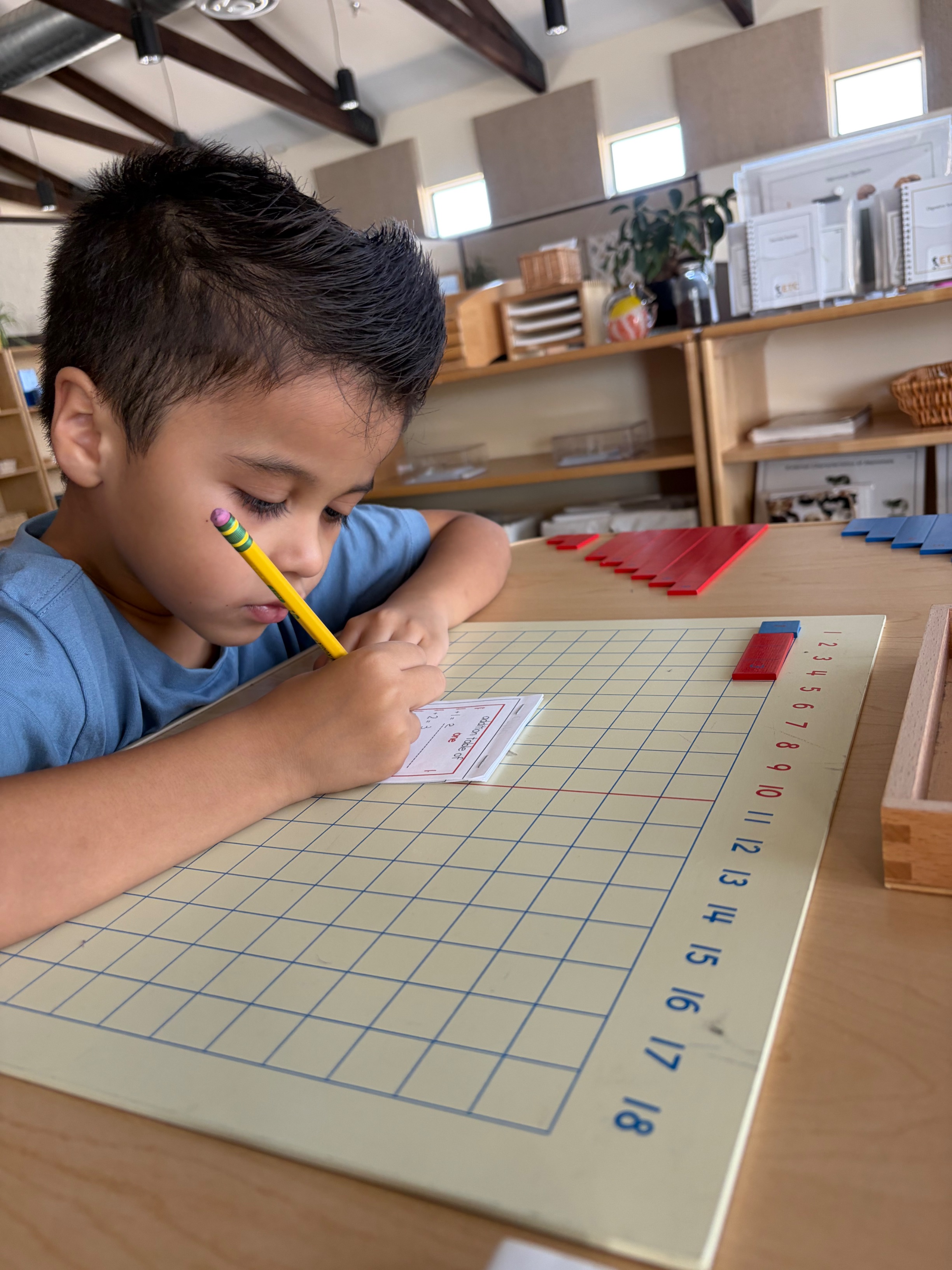 A student practicing math addition on a grid board