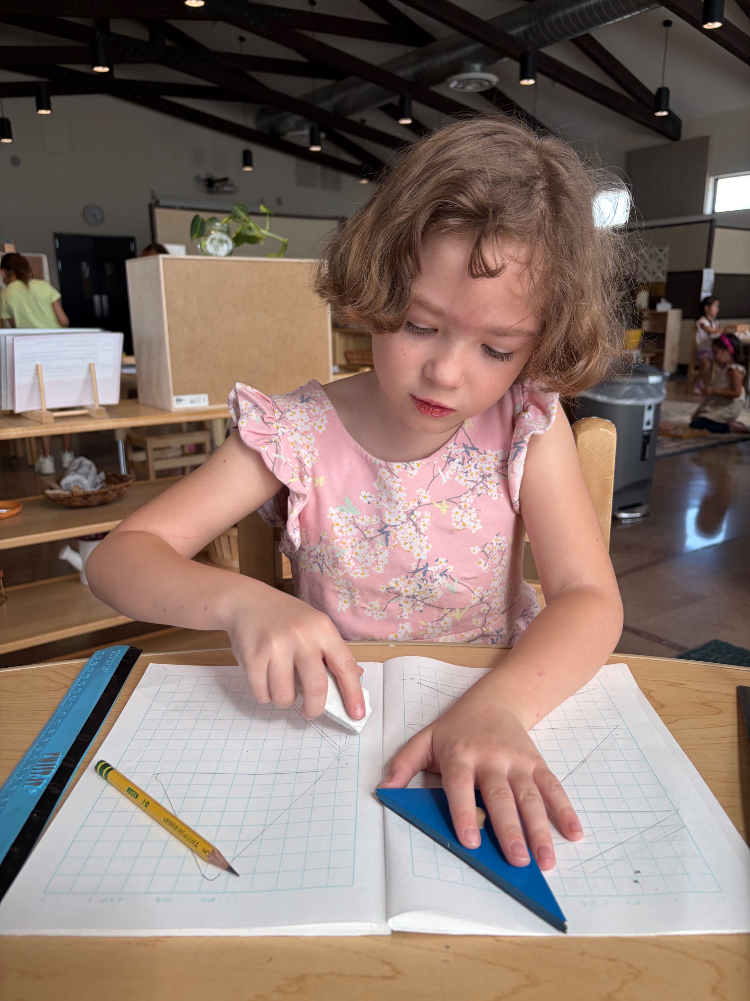 An Elementary student working with geometric shapes and drawing materials