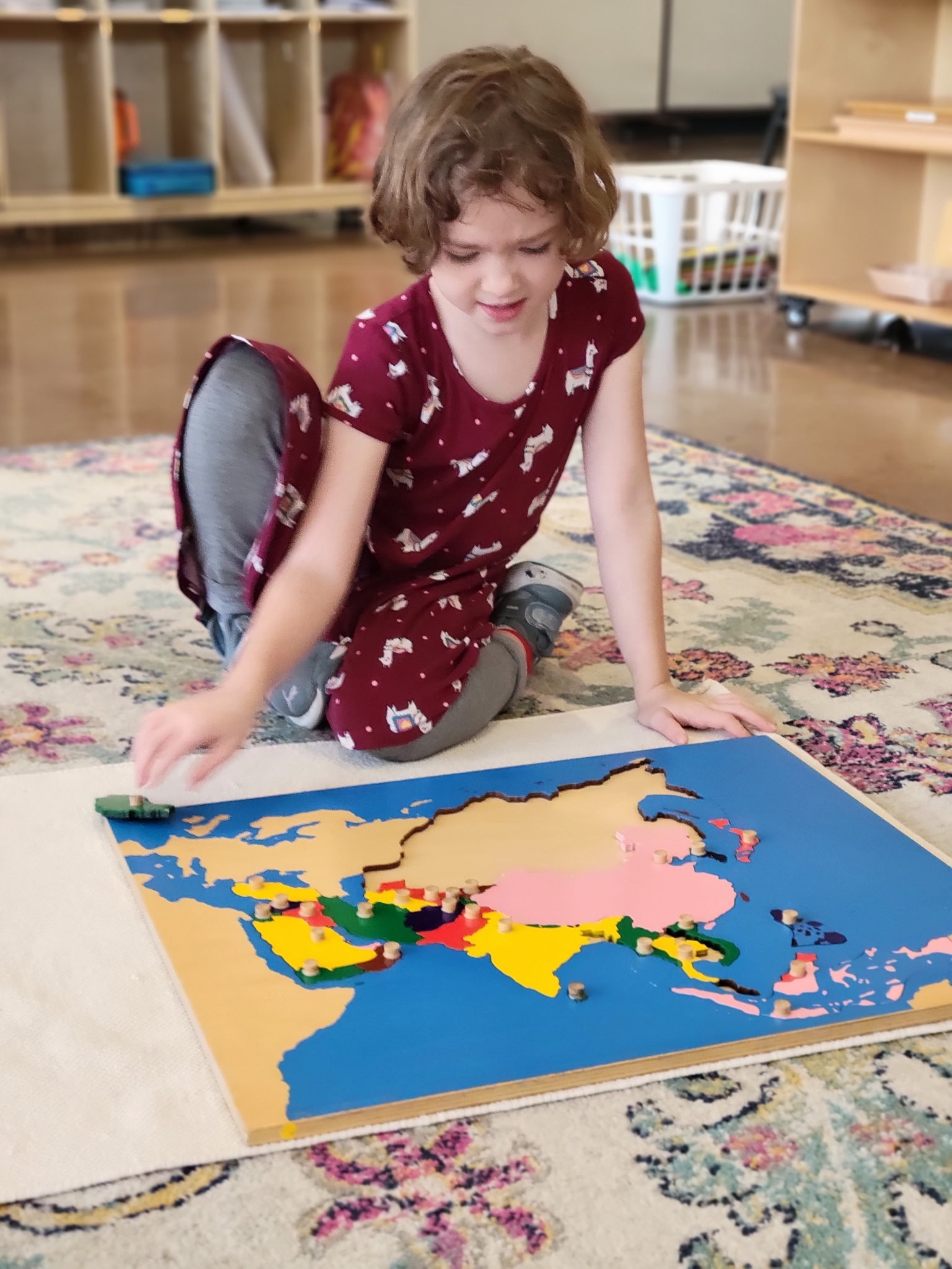 A student assembling the Montessori puzzle map of Asia