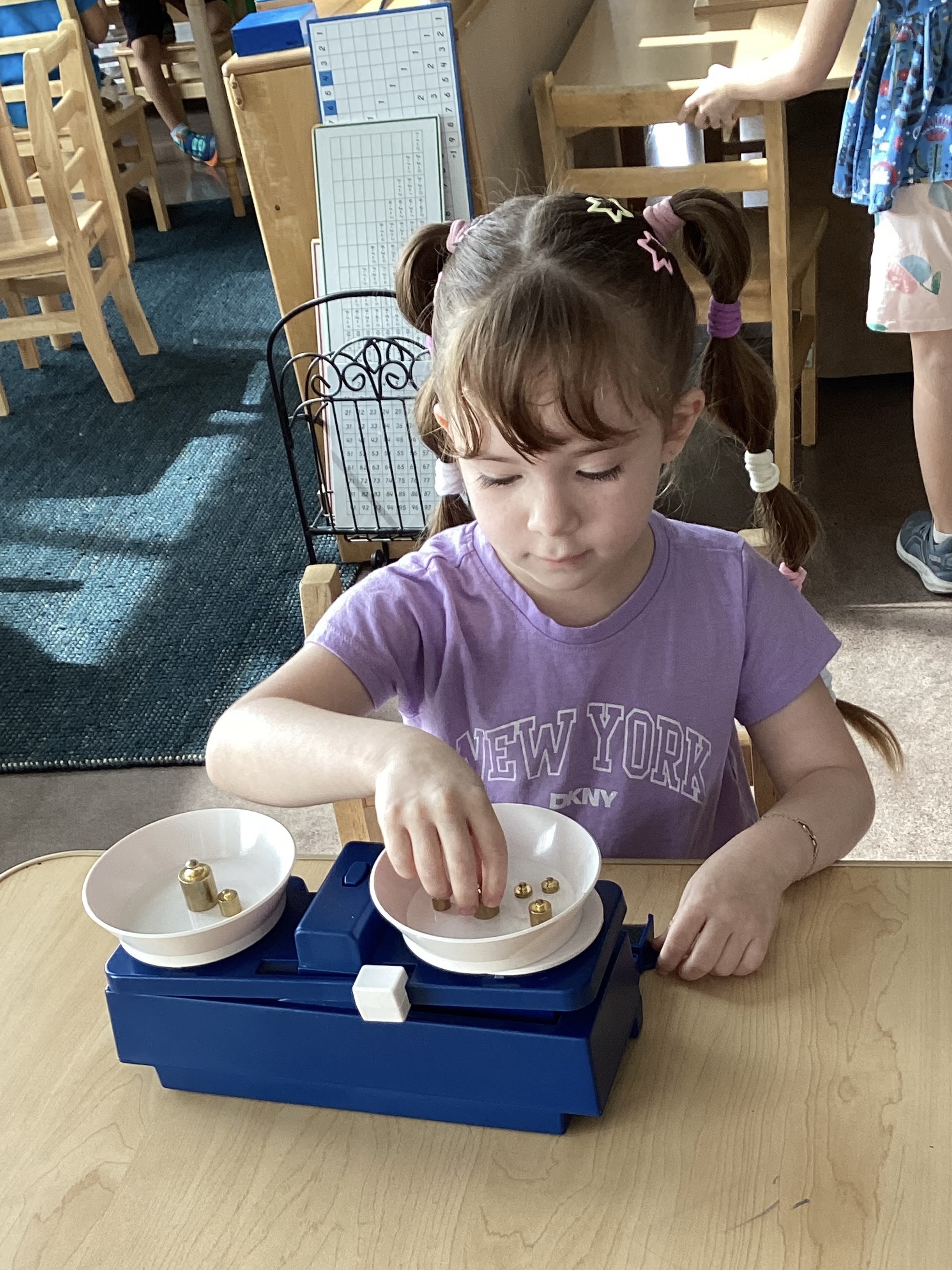 A student using a balance scale with brass weights