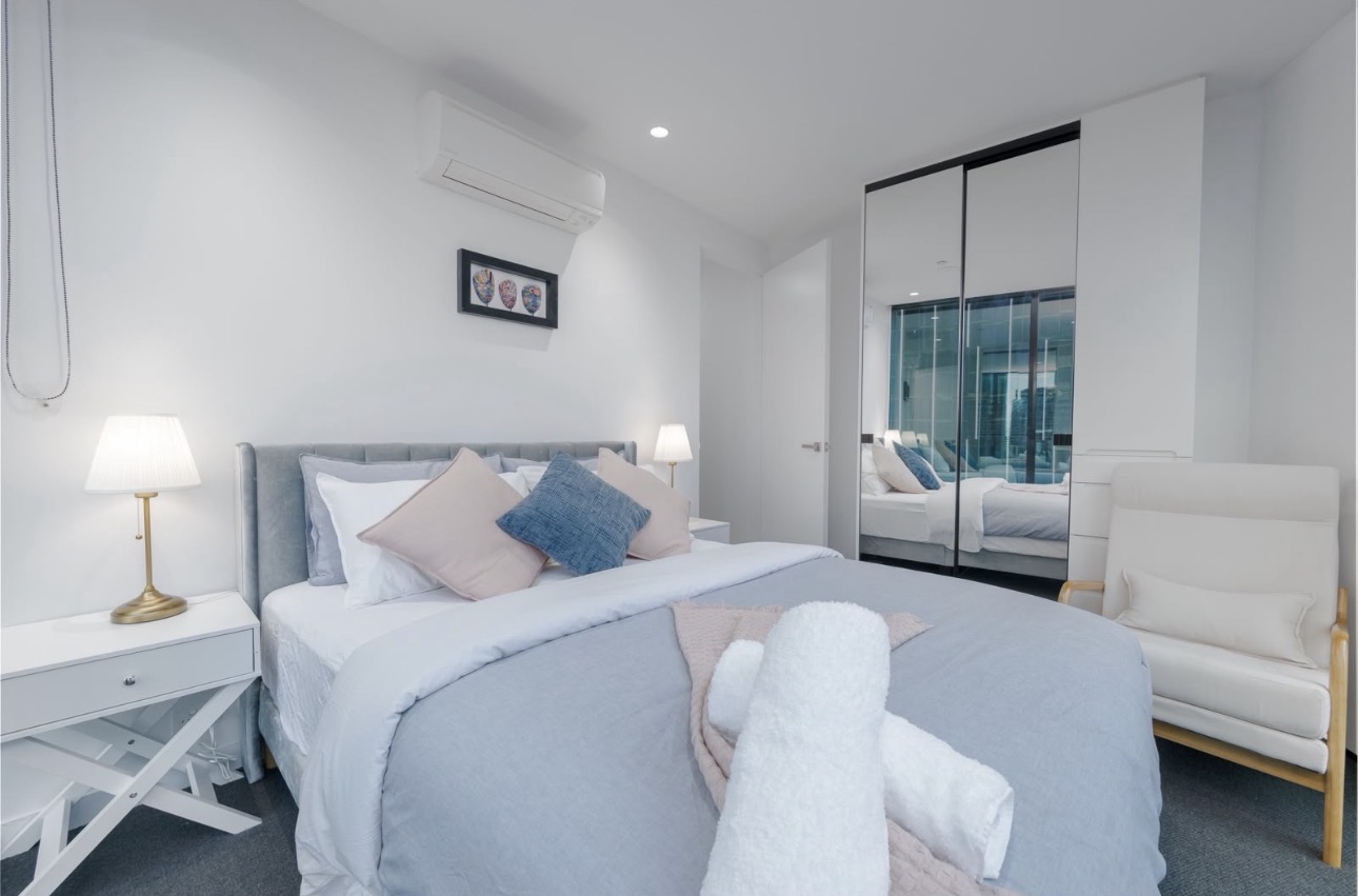 Bedroom with blue bedding and mirror wardrobe