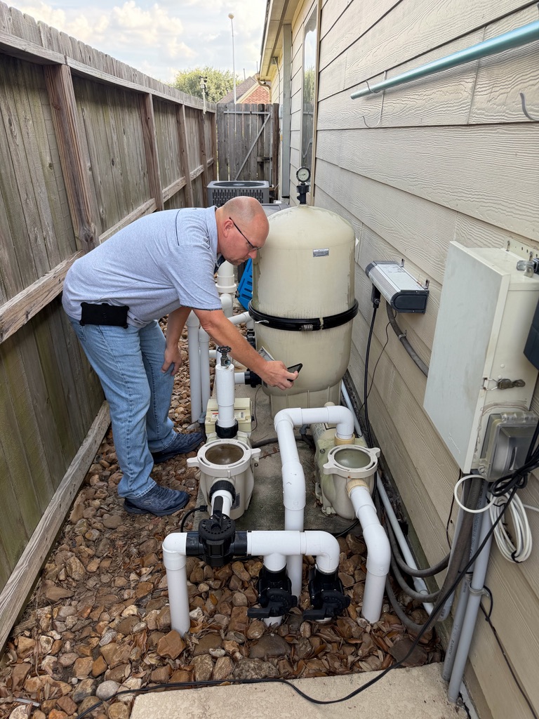 Dave Tague inspecting pool equipment and plumbing at a residential property
