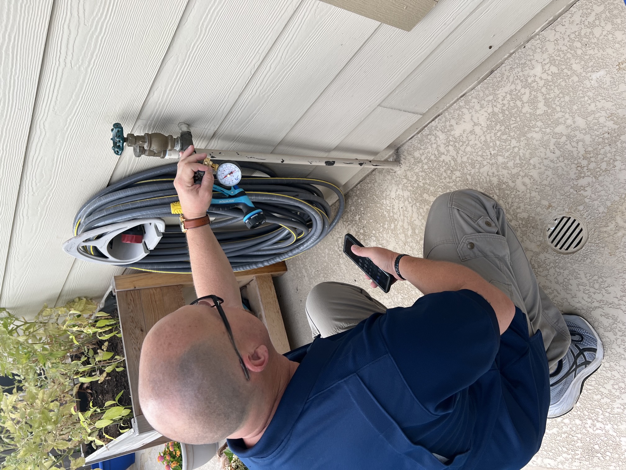 Dave Tague testing exterior water pressure with a gauge at residential spigot