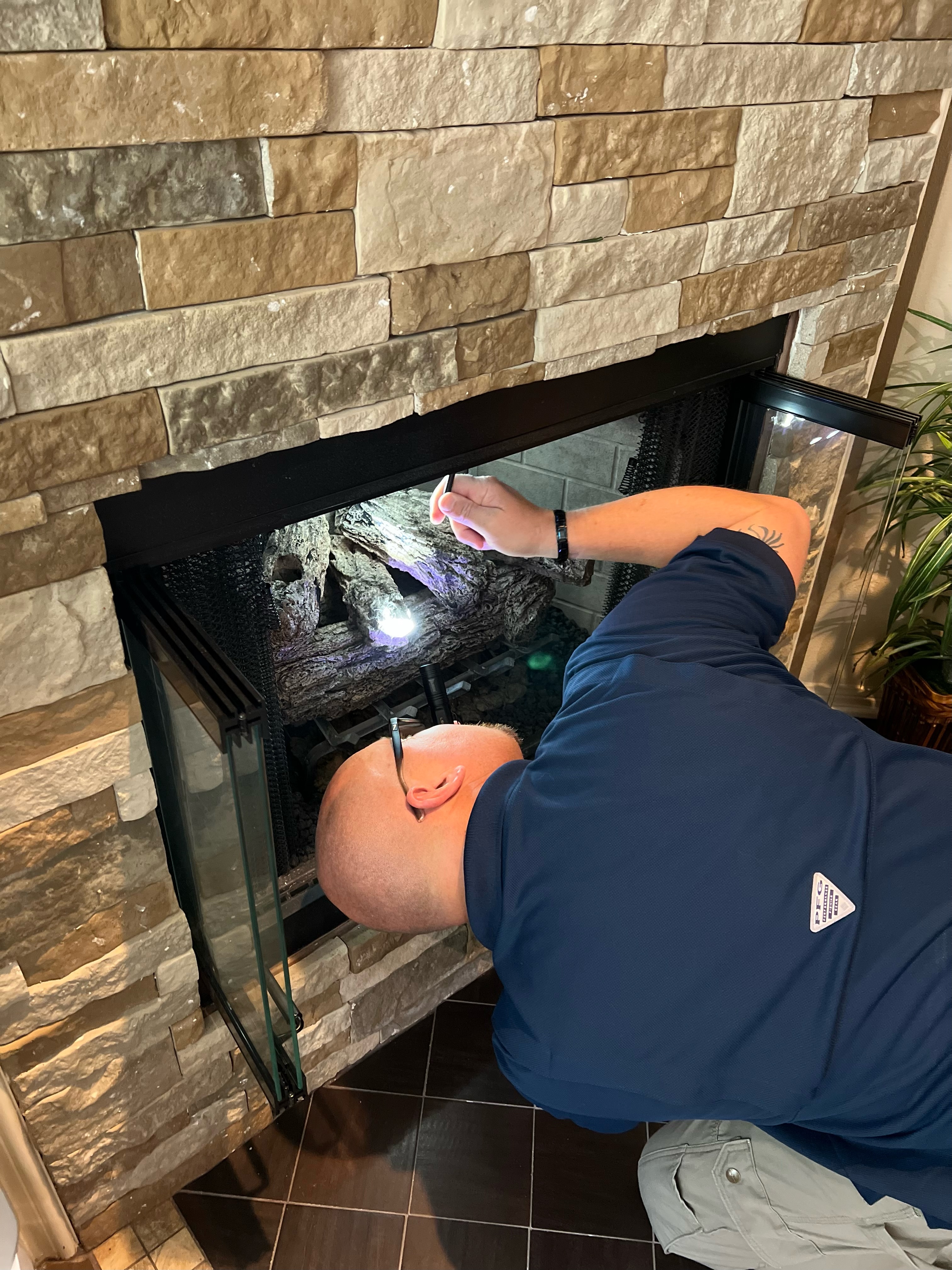 Dave Tague carefully inspecting fireplace logs and flue with flashlight
