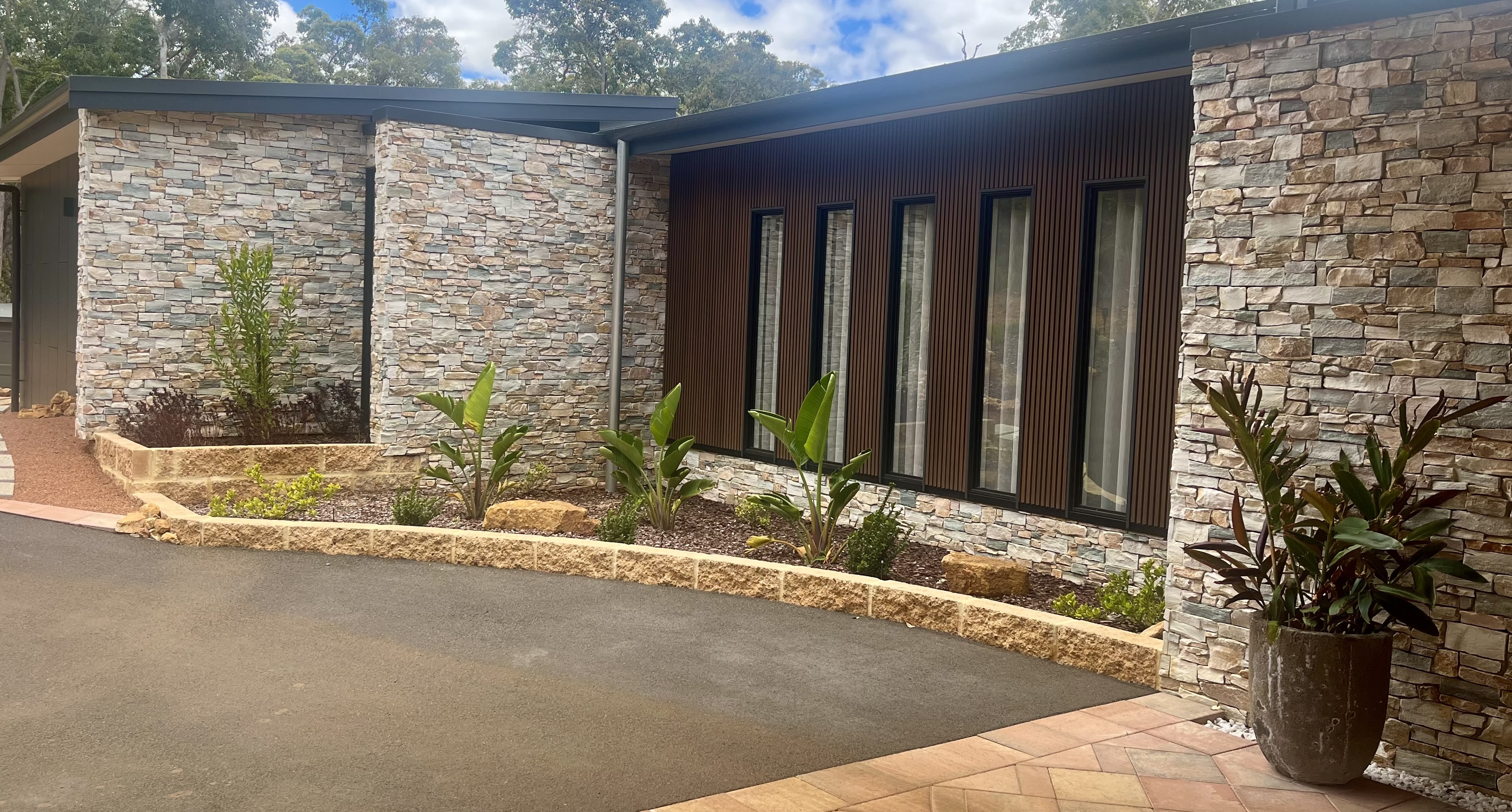 Stone-clad entrance facade with timber slat feature window